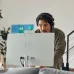 Focused view of HP All-in-One 24-cr0073d Core i5 PC with user wearing headset engaged in online activity at home.