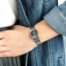 Wrist view of Casio LTP-1230D-1CDF Watch with black dial, silver markers, and date window against denim sleeve.