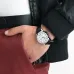 Close-up wrist view of Casio MTP-V004D-7AUDF Watch with silver dial and black strap styled with red pants and jacket.