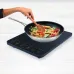 Kitchen use view of Tefal EVERYDAY SLIM IH 2200W Induction Cooker cooking stir-fried noodles with touch controls visible.