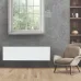 Interior view of Tesy CN 06 140 EA FinEco Cloud Heater mounted on gray wall beside armchair and shelf.