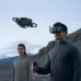 Action view of the DJI Avata 2 Fly Smart Combo Drone flying outdoors with a pilot wearing FPV goggles in a mountainous setting.
