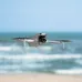 Flying view of DJI Lito 1 Drone labeled LITO 3 near ocean waves and clear blue sky.