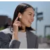 A smiling woman in a gray blazer is shown outside, touching a white HiFuture ColorBuds2 earbud in her right ear.