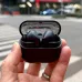 Close-up of Samsung Galaxy Buds 3 FE in black charging case held outdoors with transparent lid showing logo.