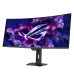 An angled view of the curved black ASUS ROG Strix OLED XG34WCDG ultrawide gaming monitor displaying a purple/pink ROG logo on the screen and stand.