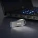 SanDisk Ultra Luxe USB flash drive placed near laptop, showcasing compact metal body and high-speed data transfer use.