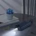Dark blue Remax RPP-550 30000mAh power bank on a table, displaying the 100% battery level and emitting a bright beam of light from its built-in flashlight.