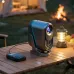 Outdoor setup with HAVIT PJ220 PRO Projector on wooden table beside lantern and apples near campfire and tent.