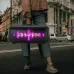 Street view of the Awei KA29 60W Portable Bluetooth Speaker carried by a person as its front panel glows with purple LED lights.