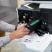 Close-up of a person's hands installing a black HP 110A toner cartridge with a blue drum into a printer.