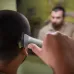 Lifestyle view of Philips MG5930/15 Trimmer used for self-haircutting at back of head with mirror reflection showing precision.