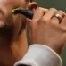 Lifestyle view of Philips OneBlade QP1624/10 Trimmer in use, trimming facial hair along cheek with bright green blade head.