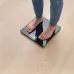Person standing on the Omron HN‑289 Digital Weight Scale measuring body weight on a wooden floor.