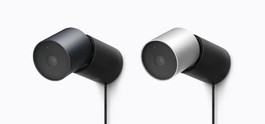 Angled side view of two LG Outdoor Cam Plug-In cylindrical outdoor security cameras in dark blue and silver attached to wall mounts.